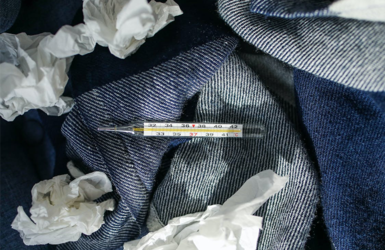 A photo of a thermometer on a blanket next to crumpled pieces of paper.
