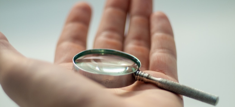 A human hand holding a magnifying glass.
