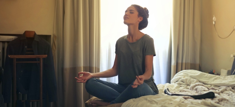 A woman in a grey shirt meditating.