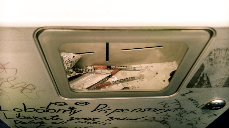 A syringe disposal box containing syringes and other paraphernalia.