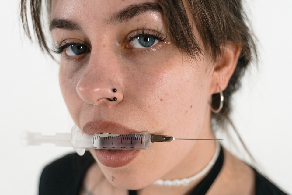 person holding a syringe in their mouth, representing non-physical signs a loved one is addicted to heroin