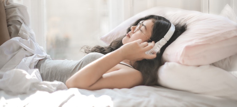Woman lying in bed and listening to music.