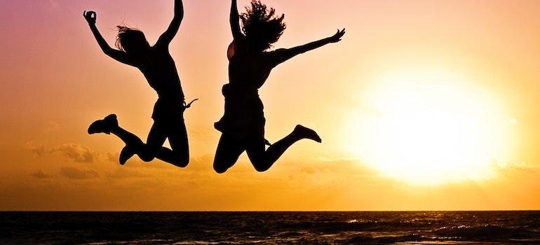 Two women jumping on a beach.