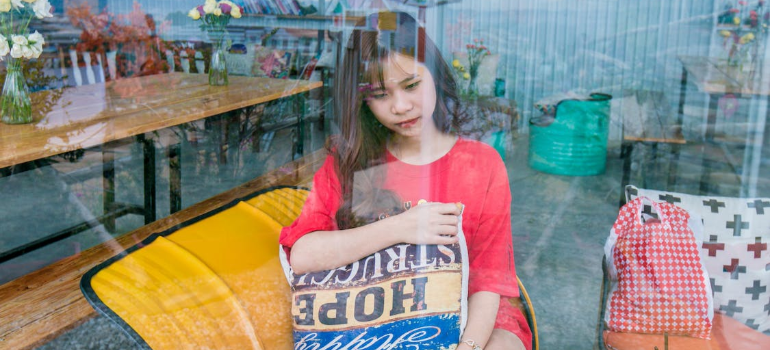 A young Asian woman sitting on a yellow sofa with a sad expression.