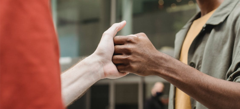A close-up of two friends shaking hands outdoors.