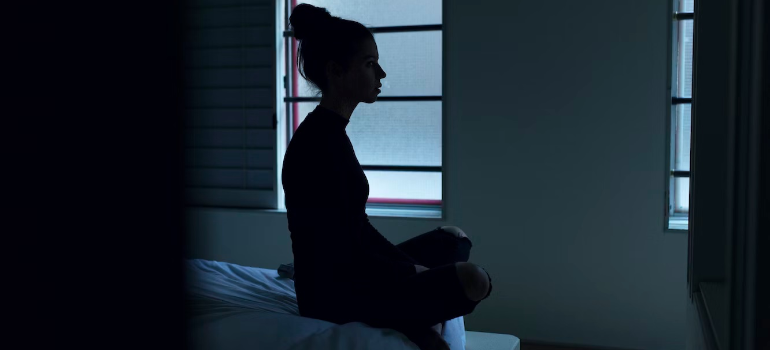 A silhouette of a woman sitting on a bed, unable to sleep.