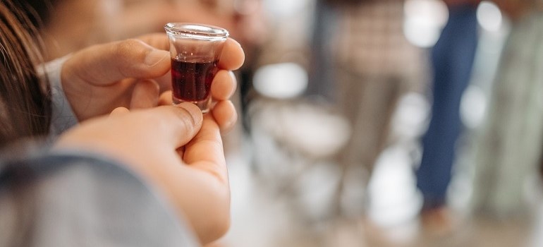 Person holding alcohol during communion.