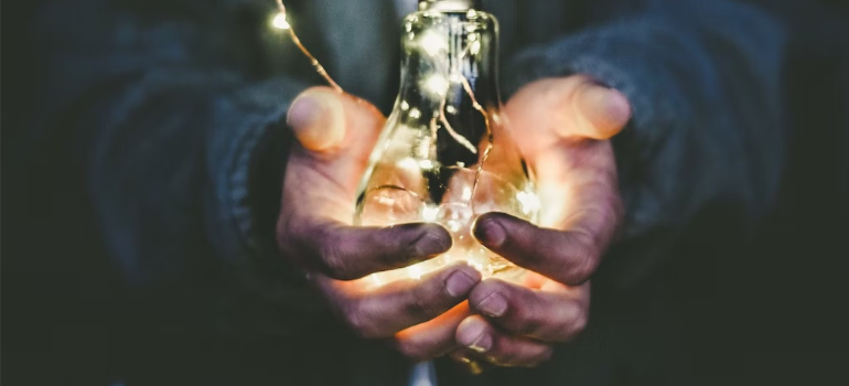 A close-up of a person’s hands holding a light bulb.