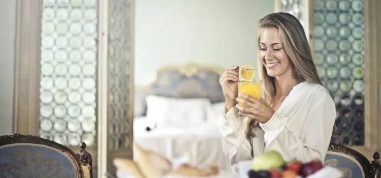 A young woman drinking orange juice and enjoying herself in her bedroom