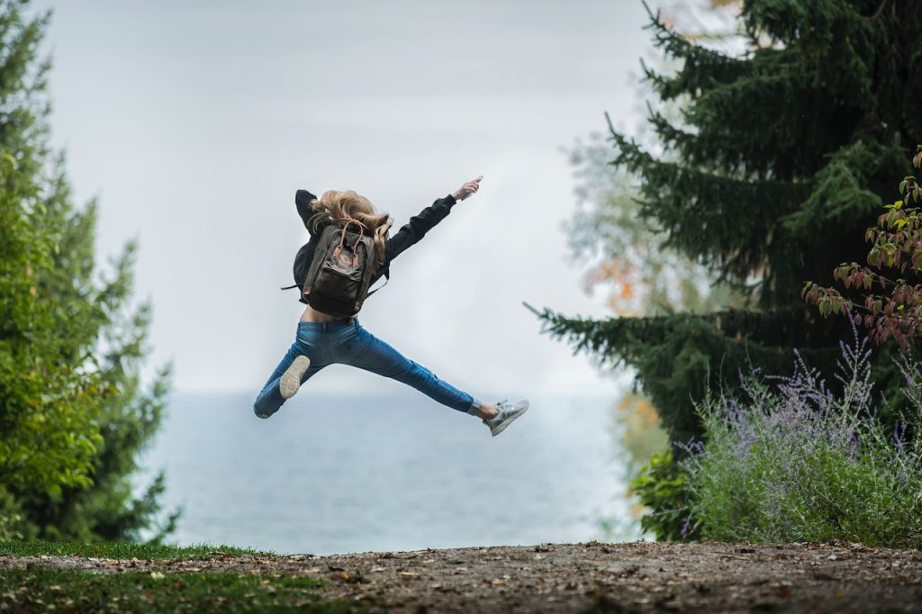 Person jumping in front of a scenic view in the forest