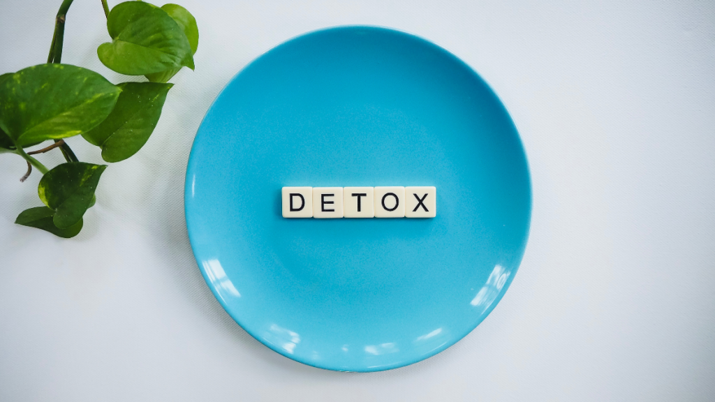 Cubes with letters that read 'DETOX' on a plate with a green plant next to it